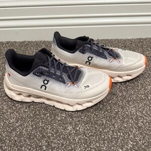 On Running Cloud tilt cream and dark gray shoes with Orange Accents